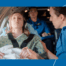 a woman in a hospital gown is laying on a stretcher in an airplane